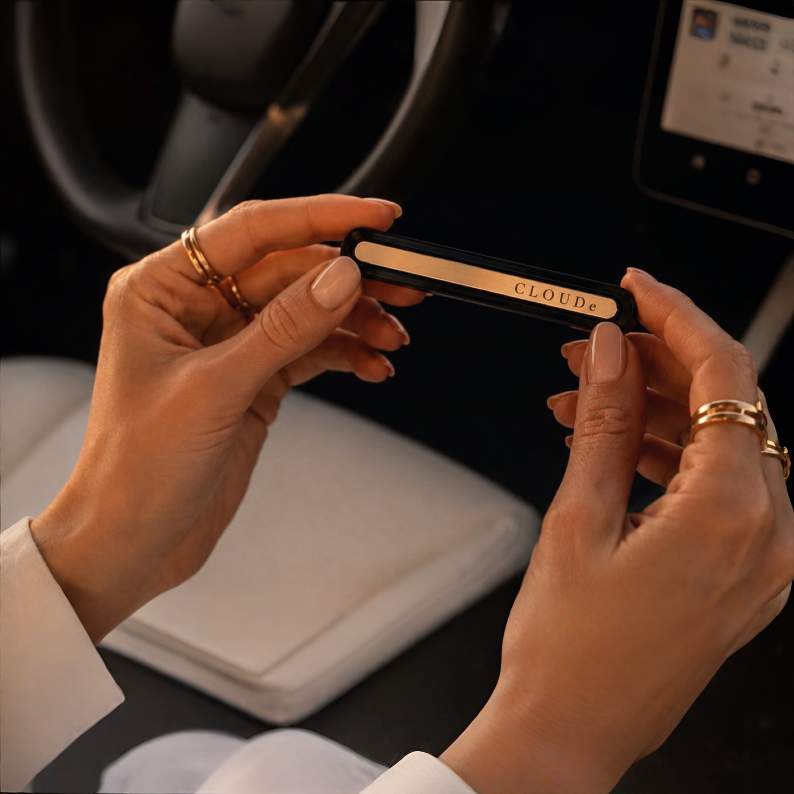 Woman holding CLOUDe Scent car fragrance diffuser inside car, gold aluminum bar with engraved logo